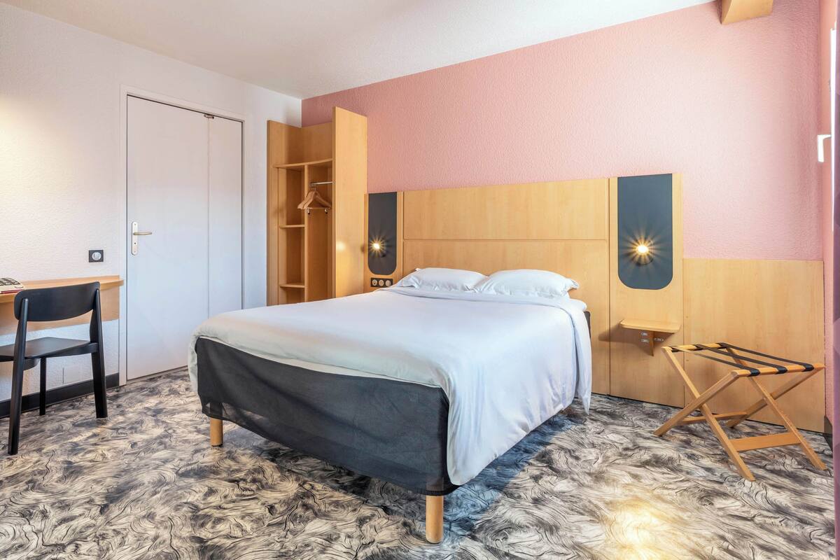 A bedroom with a bed, a desk, and a wardrobe.