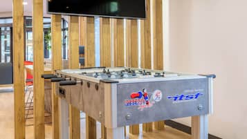 A foosball table with a logo and the text "Official Partner" in a room with wooden paneling and a television mounted on the wall.