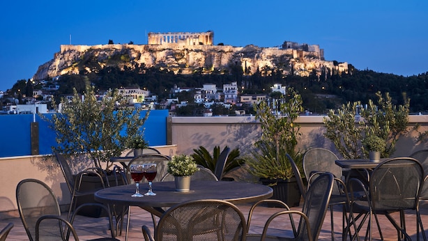A terrace with outdoor seating and a view of a historic building on a hill. - Arion Athens Hotel (Athens)
