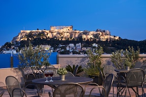 A terrace with outdoor seating and a view of a historic building on a hill.