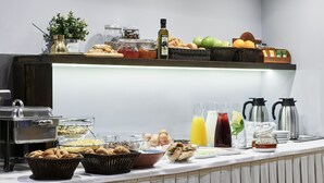 A buffet setup with various food items, beverages, and condiments. - Arion Athens Hotel (Athens)