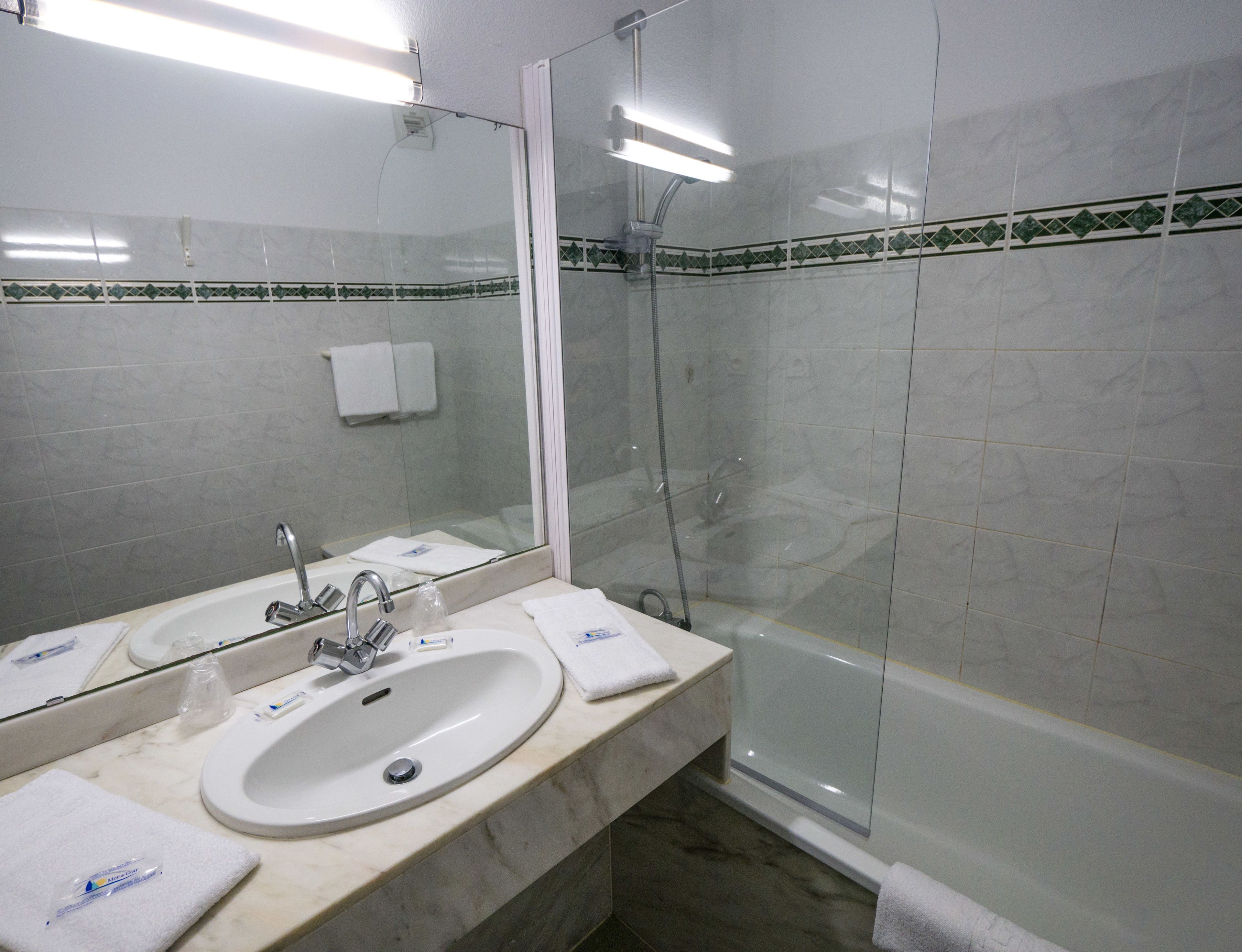 Un baño con lavamanos, espejo y ducha.