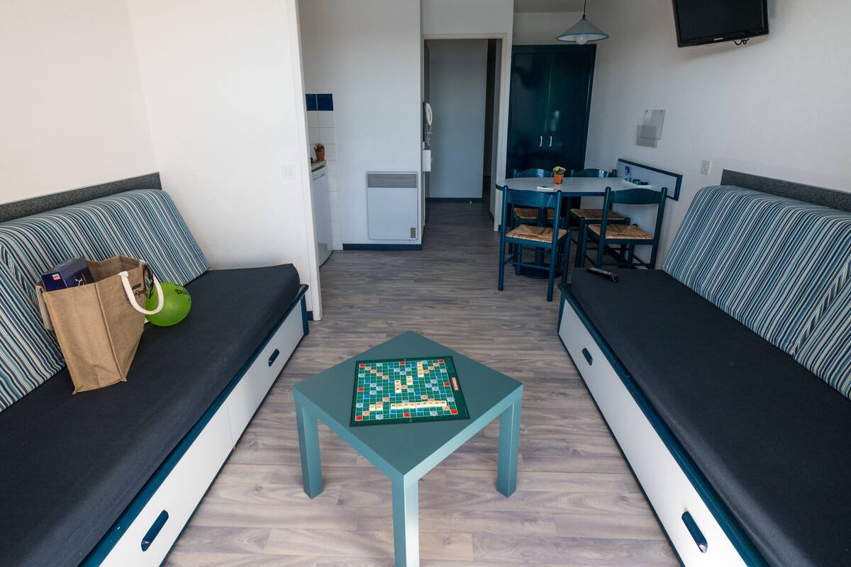 A compact living space with two sofas, a small table, and a dining area.