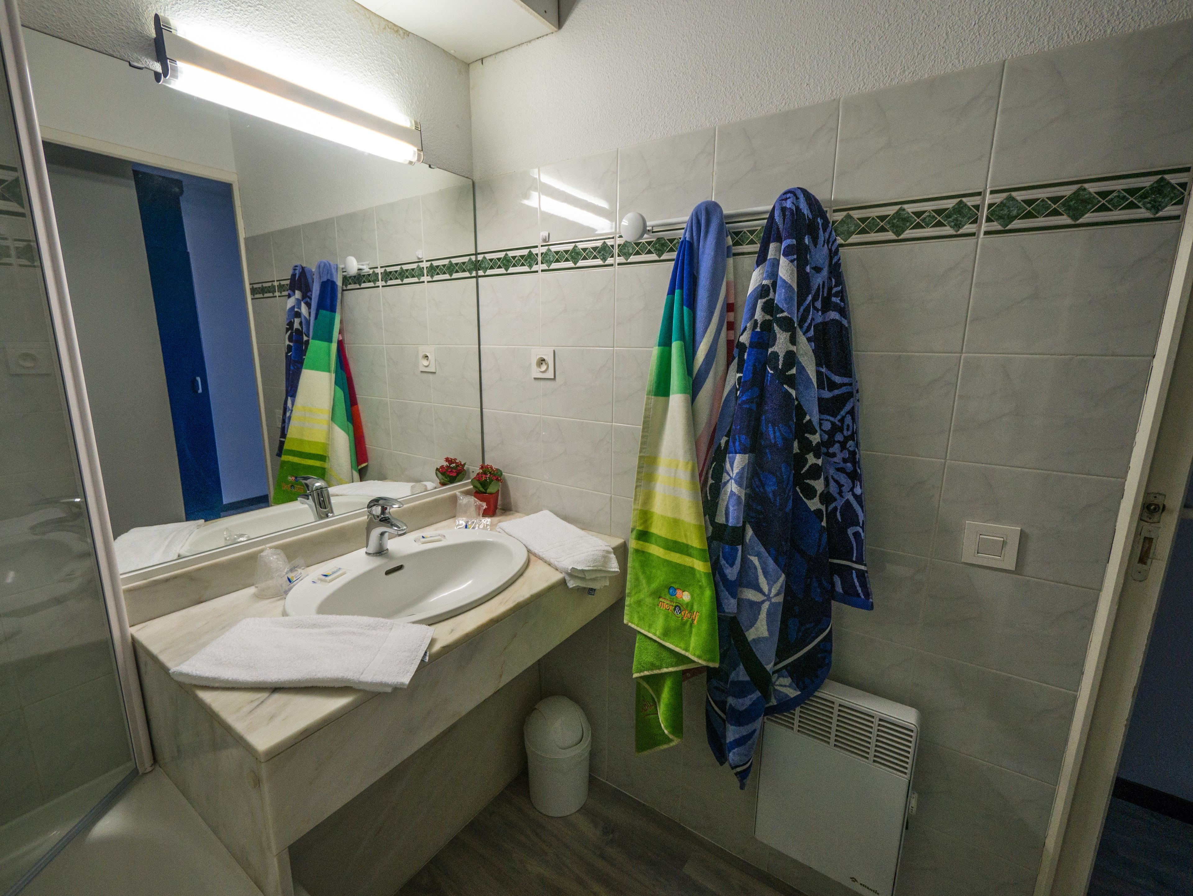 A bathroom with a sink, mirror, and towel rack.