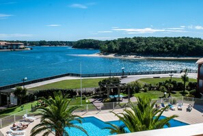 Zona de piscina con sillones de descanso y vista al mar.
