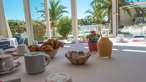 A breakfast table with croissants, coffee cups, and a fruit pitcher. - Résidence Le Boucanier (Vieux-Boucau-les-Bains)