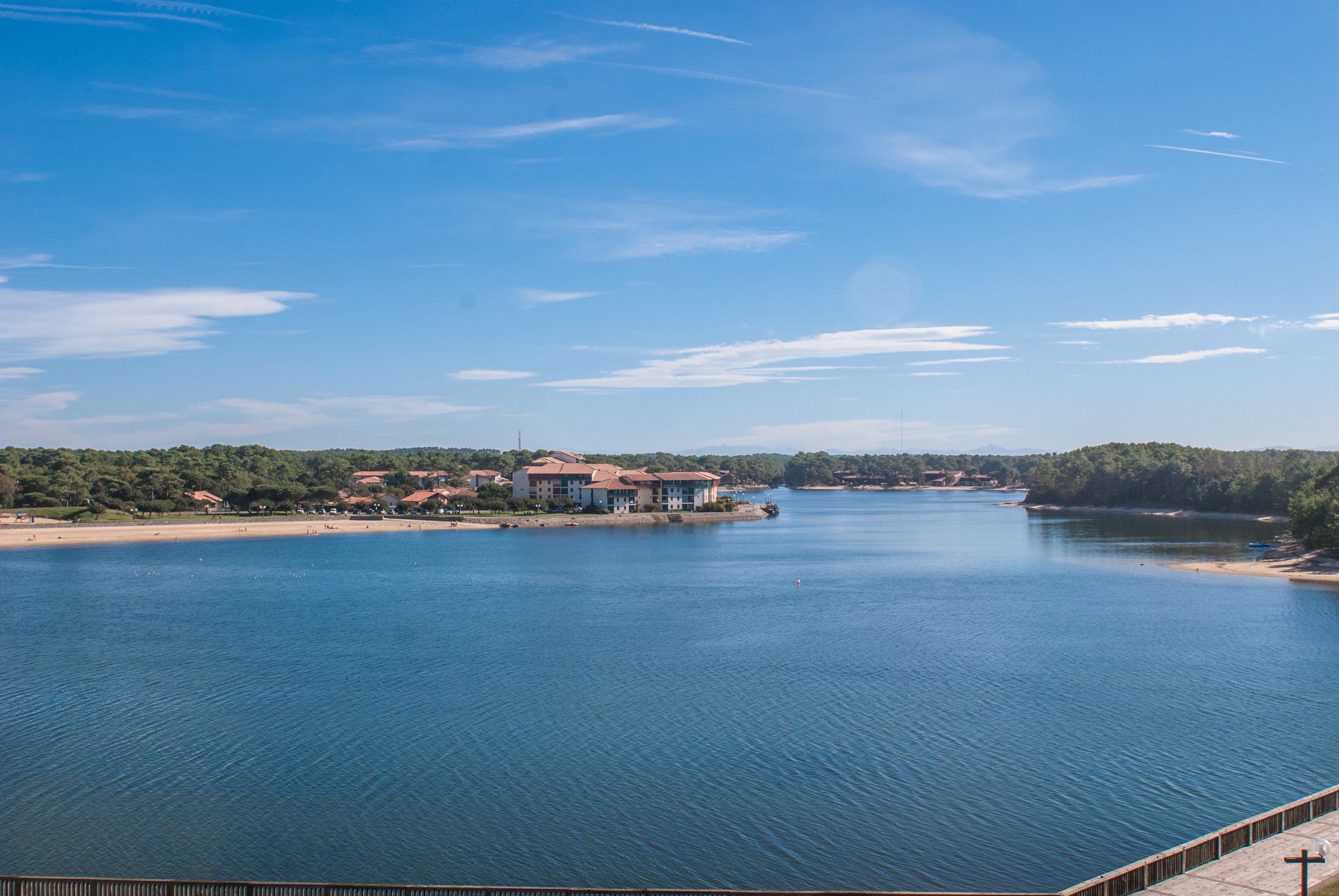 A waterfront property with a large building, a dock, and a bridge in the background.