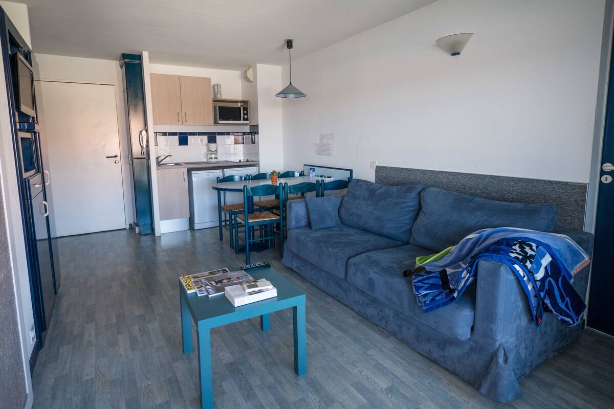 A compact living space with a kitchenette, a dining area, and a seating area with a sofa and a coffee table.