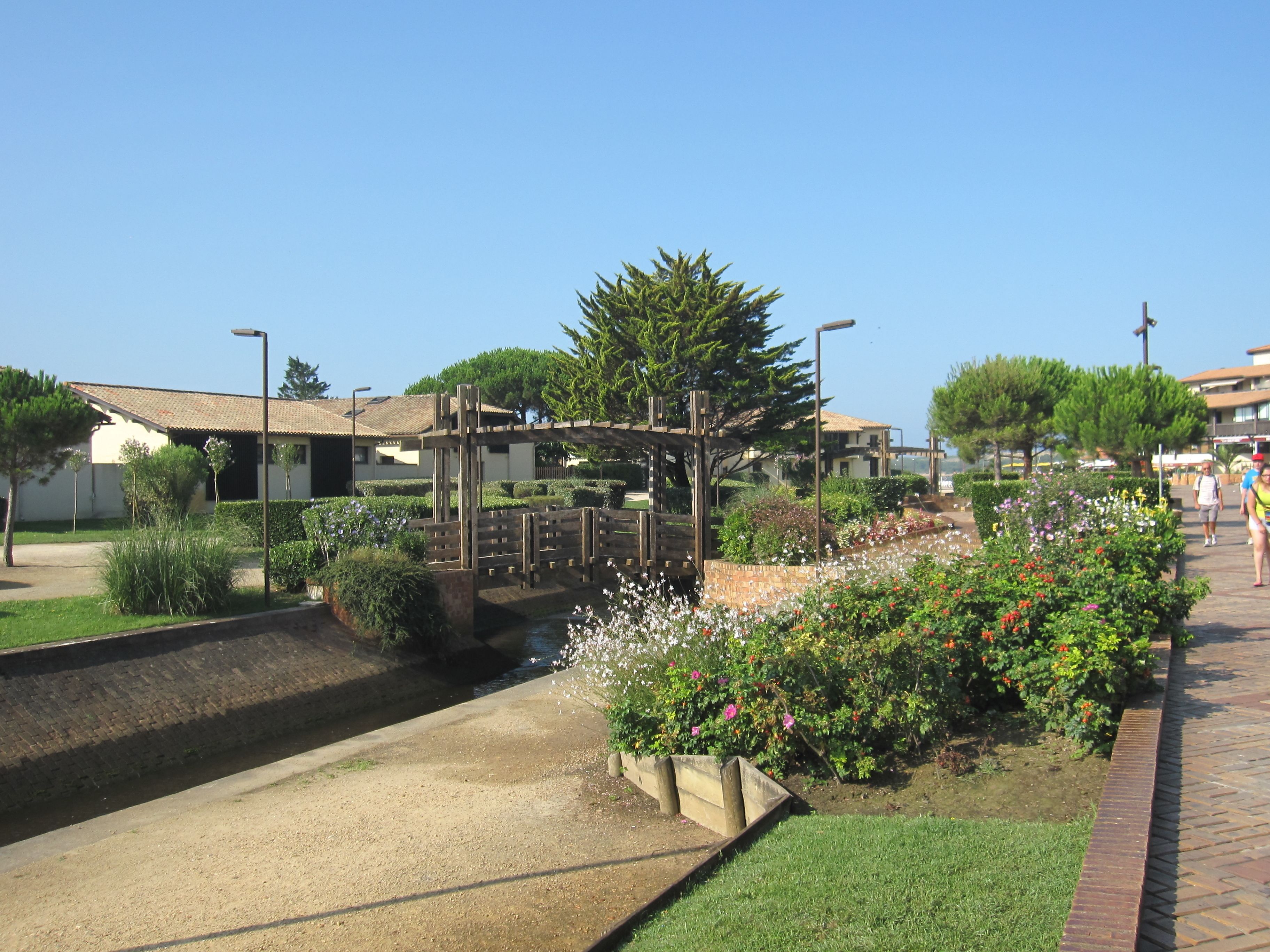 A garden with a water feature, a wooden pergola, and a brick pathway.