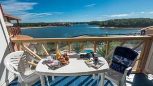 A balcony with a table set for breakfast, overlooking a body of water and a beach. - Résidence Le Boucanier (Vieux-Boucau-les-Bains)