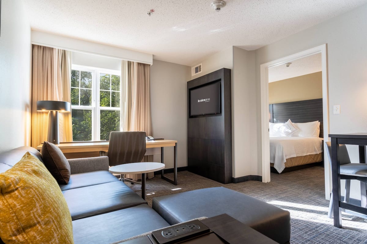 A hotel room with a sofa, a desk, a bed, and a television.