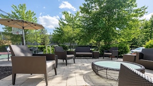 An outdoor patio area with wicker furniture, a round table, and a basketball hoop. - Residence Inn by Marriott Princeton at Carnegie Center (Princeton)