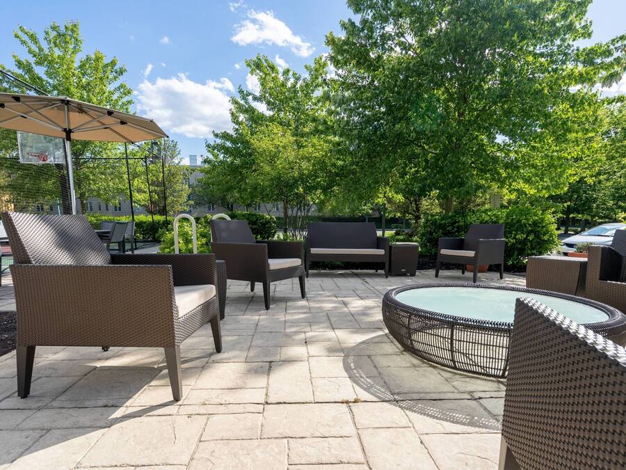 An outdoor patio area with wicker furniture, a round table, and a basketball hoop.