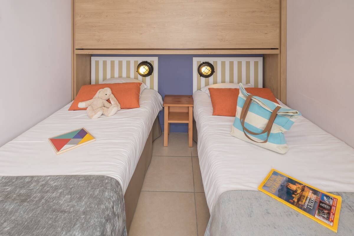 A twin room with two beds, a nightstand, and a small table.