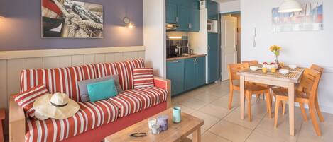 A living area with a striped sofa, a wooden coffee table, and a dining table with chairs.