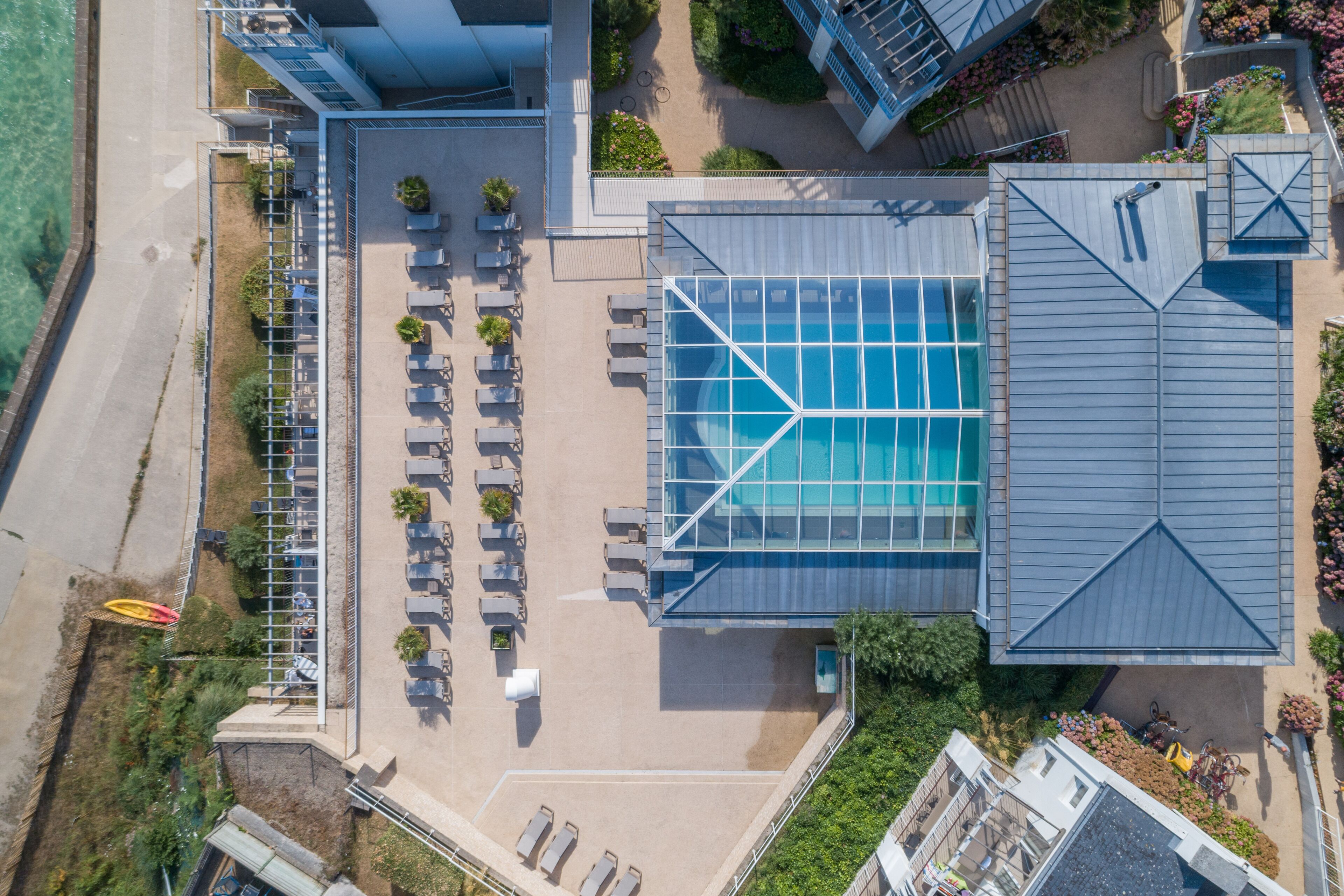An aerial view of a hotel with a swimming pool, outdoor seating area, and a parking lot.
