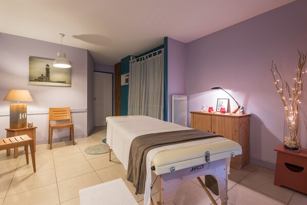 A bedroom with a bed, a wooden chair, a desk, a lamp, a picture on the wall, and a small cabinet.