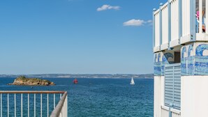 Uitzicht op de kust met een heldere lucht, een rotsformatie en enkele zeilboten op het water.