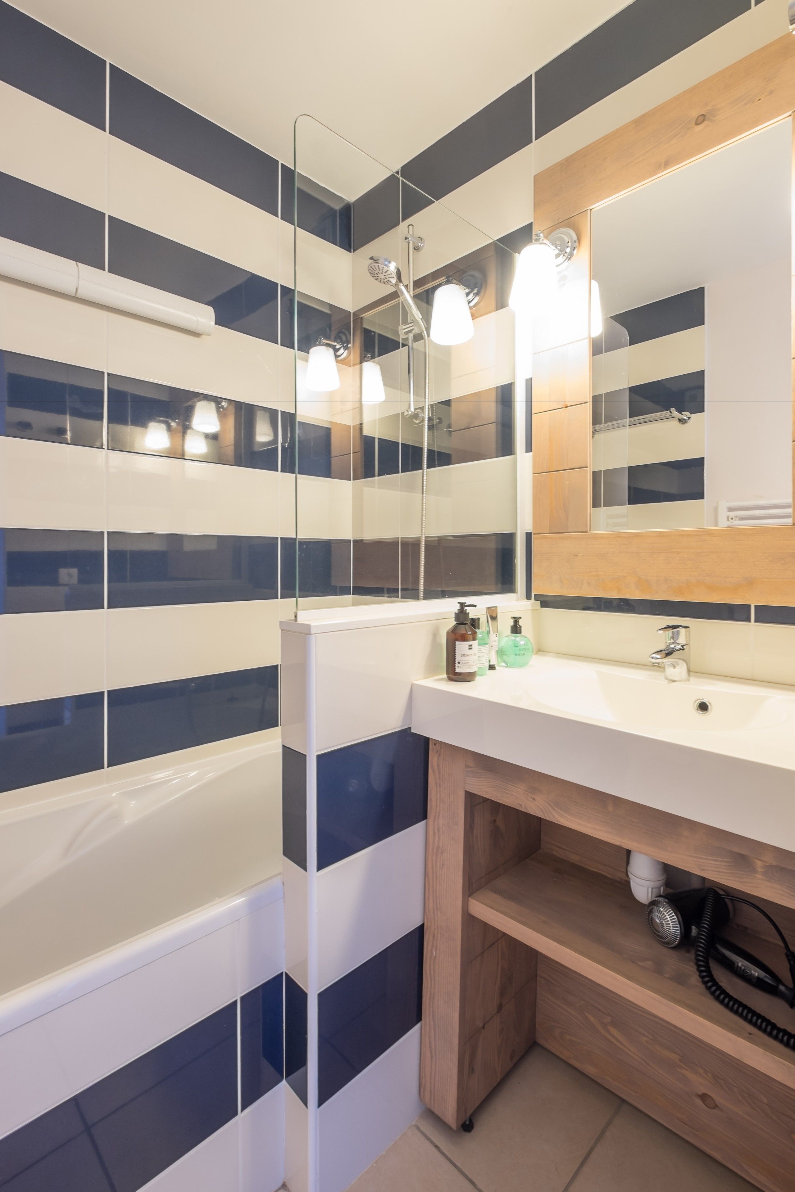 Ein modernes Badezimmer mit Waschbecken, Spiegel und Wandfliesen mit Streifenmuster.