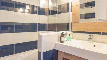 Ein modernes Badezimmer mit Waschbecken, Spiegel und Wandfliesen mit Streifenmuster.