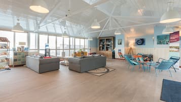 A spacious living area with a high ceiling, large windows, and a variety of seating options including sofas and chairs.