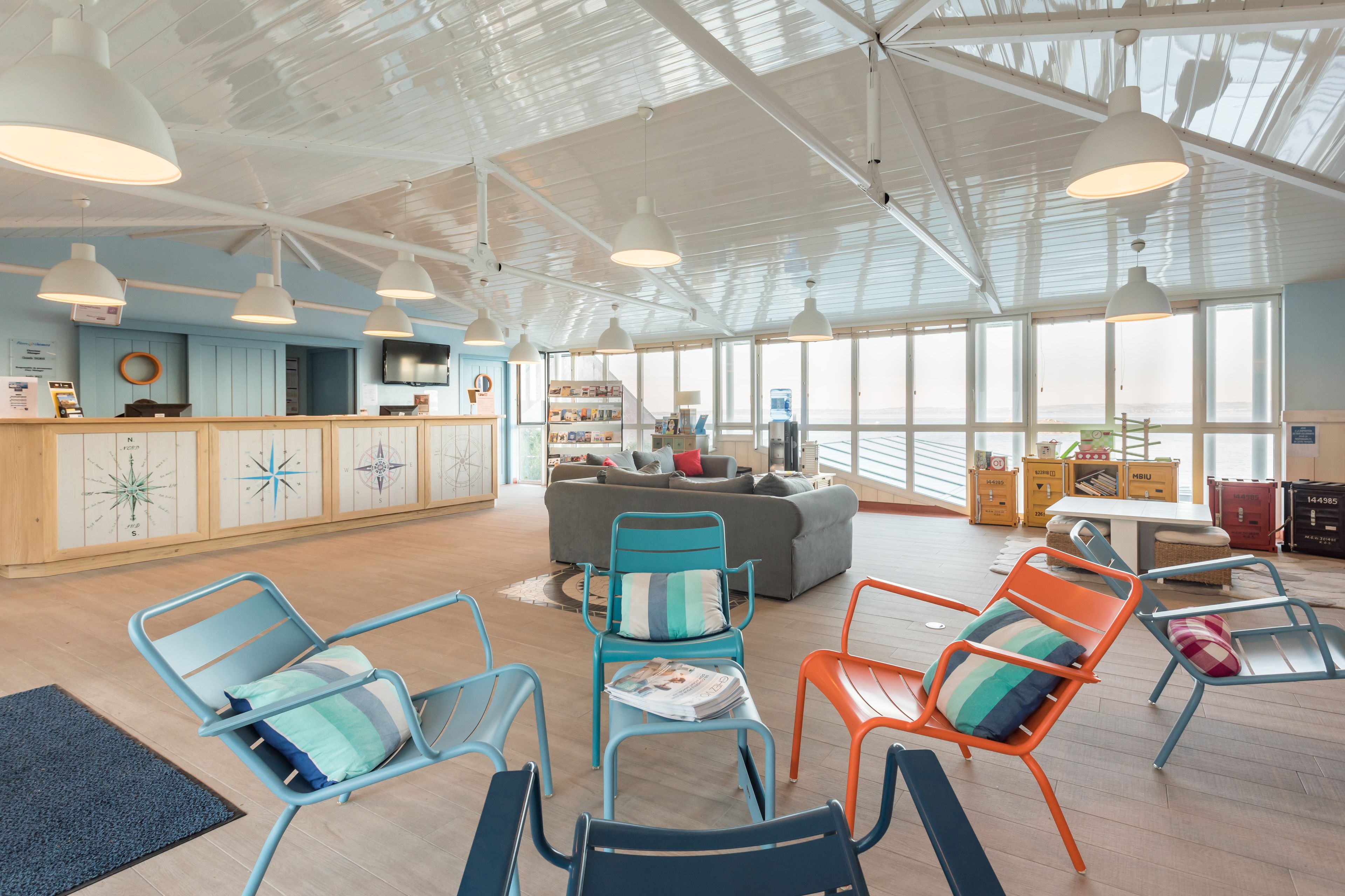 A spacious room with a high ceiling, large windows, and a seating area with colorful chairs.