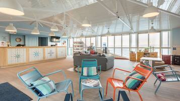A spacious room with a high ceiling, large windows, and a seating area with colorful chairs.