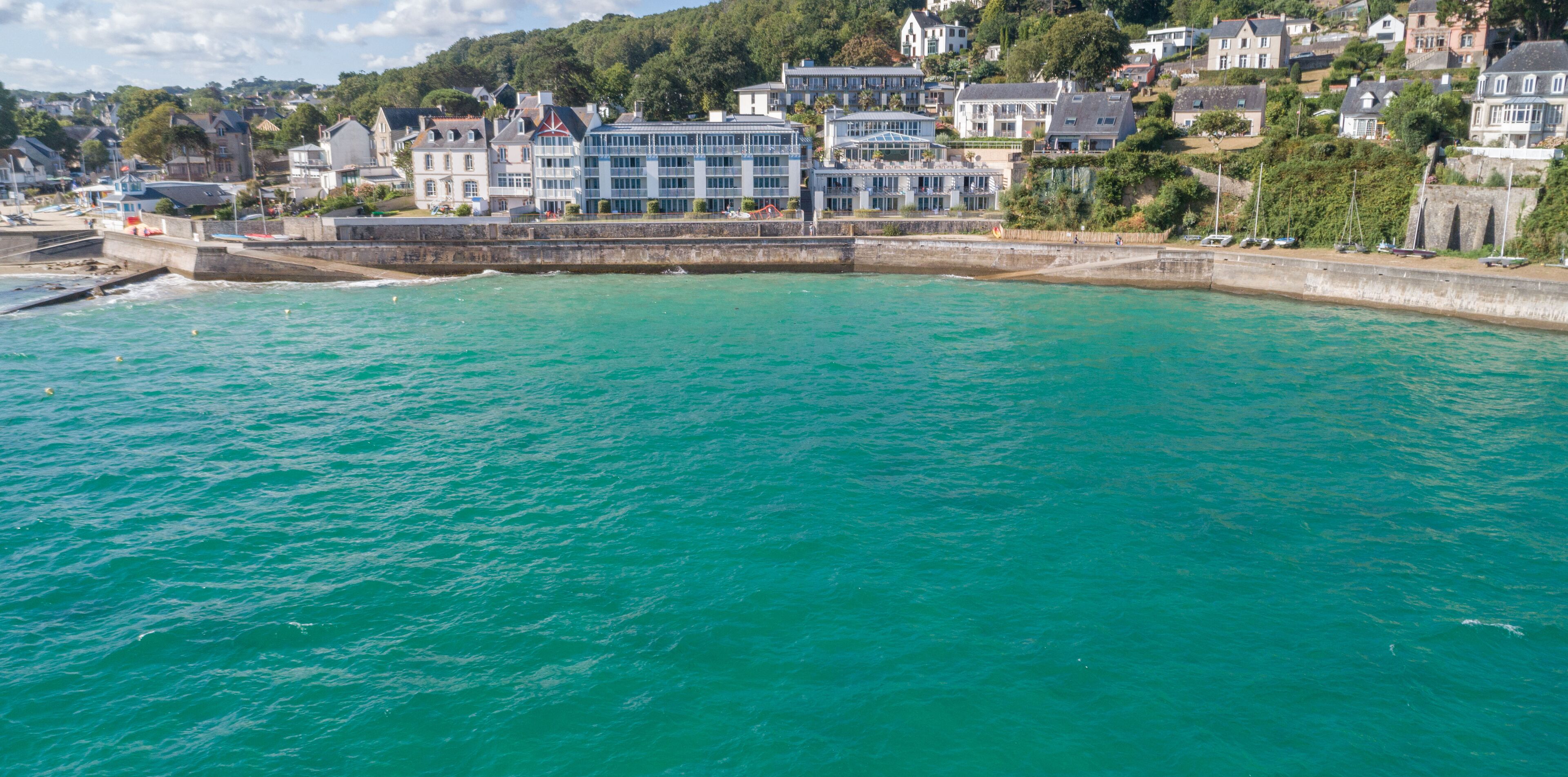 A coastal town with a prominent waterfront promenade, a large modern building, and traditional houses.