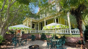 A yellow house with a porch, green chairs, and a fire pit. - Rothschild-Pound House Inn (Columbus)