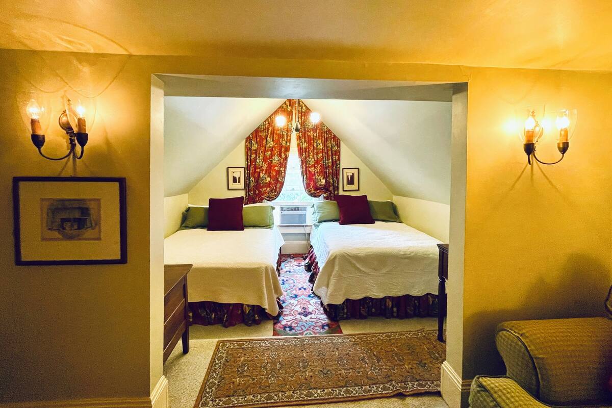 Une chambre avec deux lits, un lustre et un tapis à motifs.