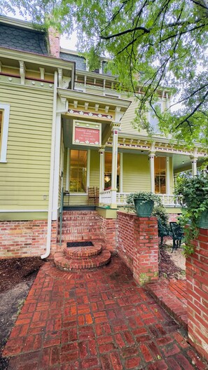 A two-story house with a porch and brick steps leading to the entrance.