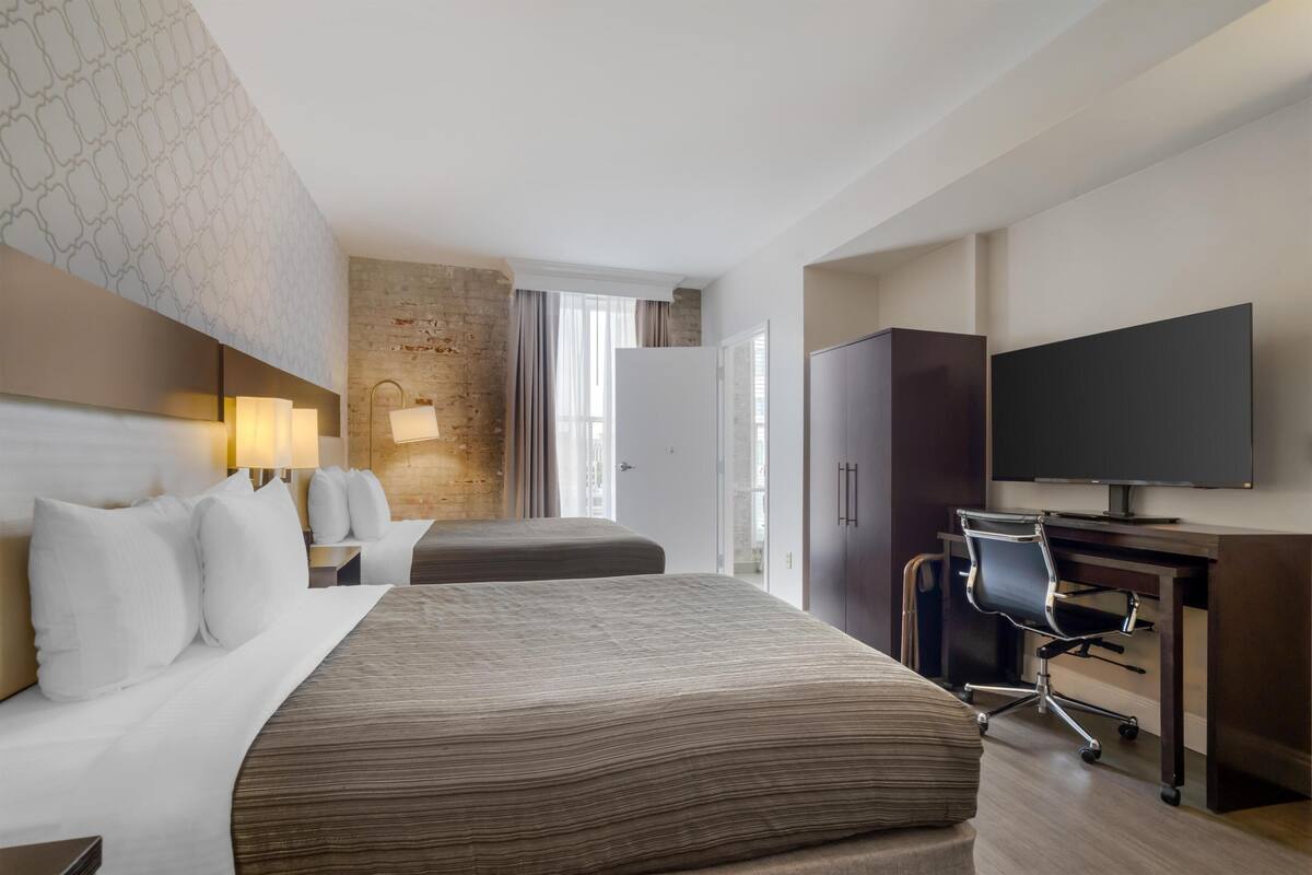 Hotellihuone, jossa on suuri sänky, työpöytä tuolilla, televisio ja vaatekaappi.