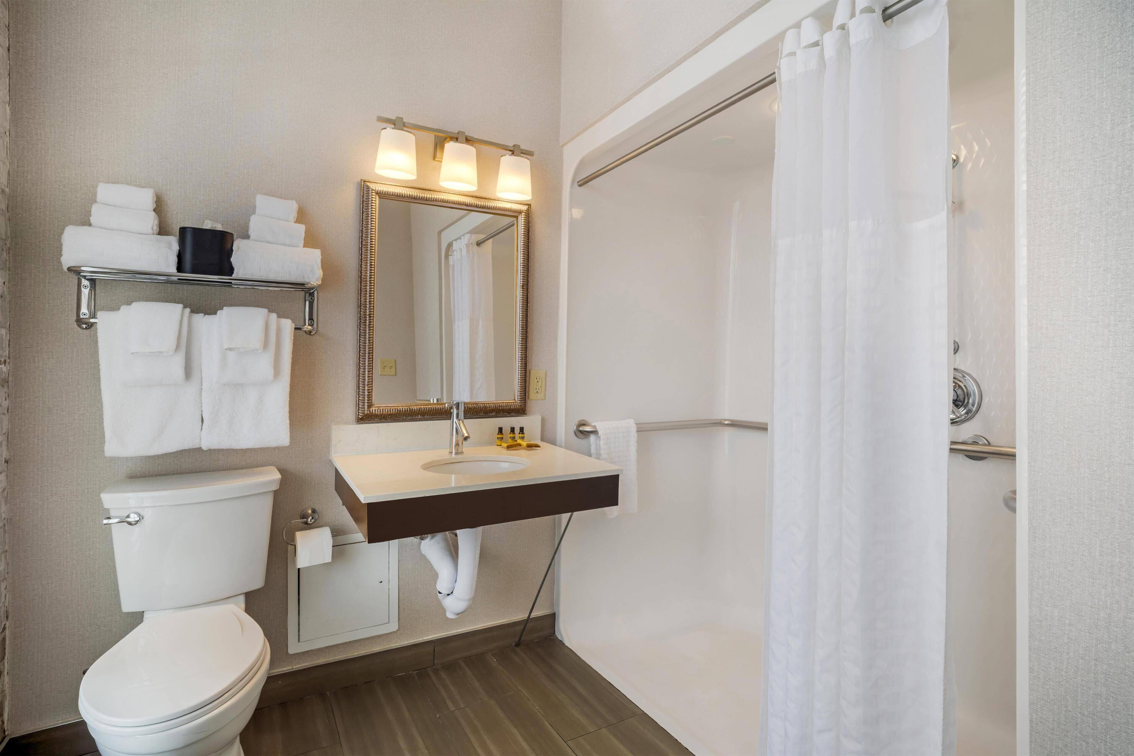 A bathroom with a toilet, sink, mirror, towel rack, and shower curtain.