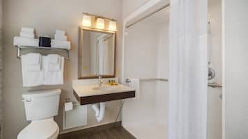 A bathroom with a toilet, sink, mirror, towel rack, and shower curtain.