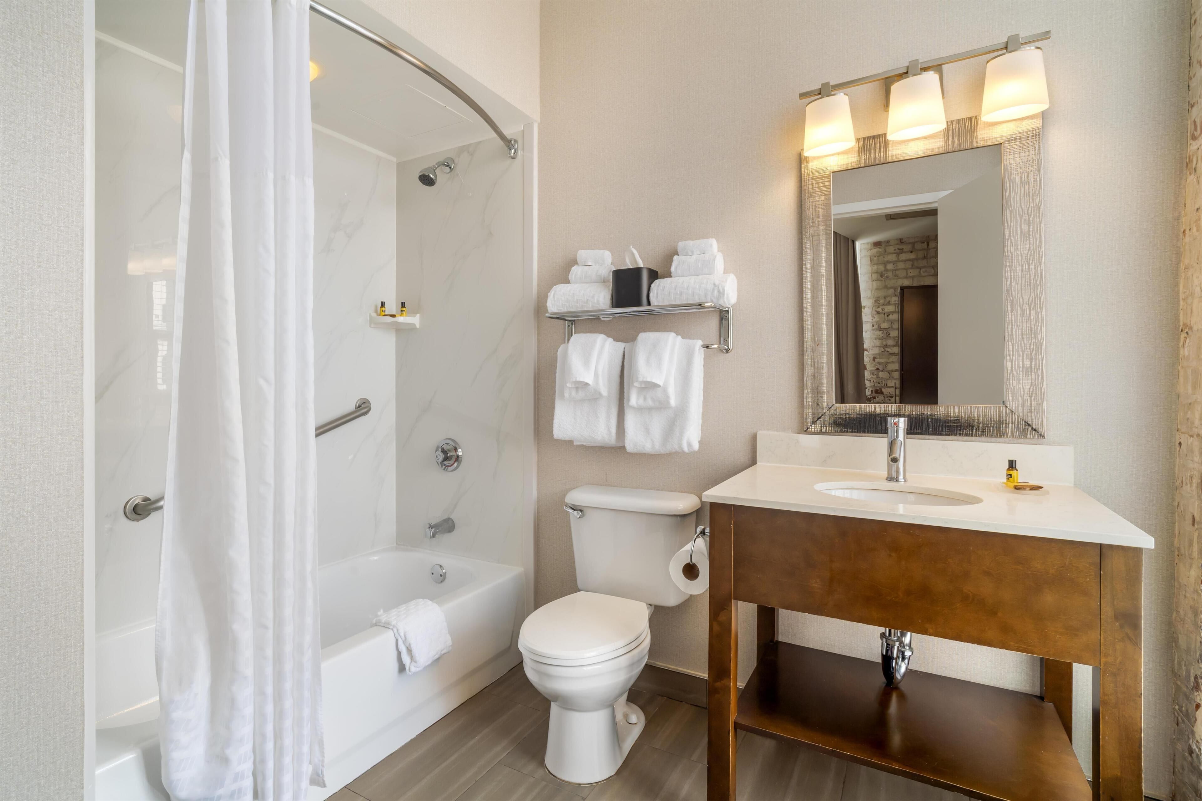 A modern bathroom with a bathtub, toilet, and vanity.
