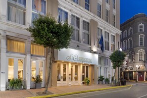 Un hotel con fachada clásica, ventanas amplias y un cartel llamativo.
