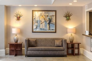 A living room with a sofa, two side tables with lamps, and a framed painting on the wall.