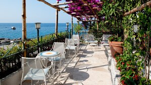 A terrace with white metal chairs and tables, overlooking the sea. - Hotel Aurora (Amalfi)
