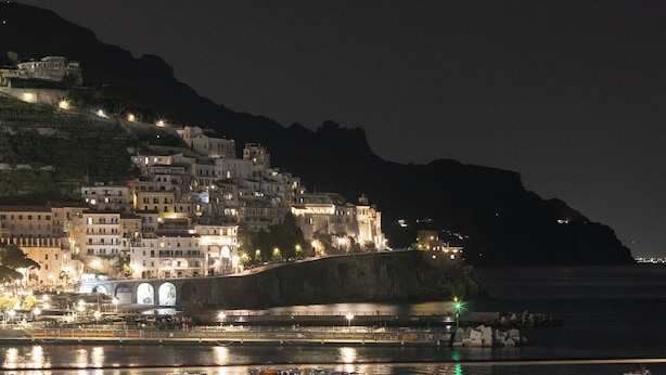 A poolside view with a view of a coastal town at night. - Hotel Aurora (Amalfi)