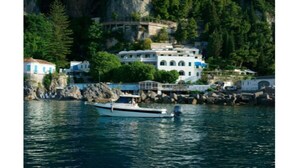 A boat docked near a coastal building surrounded by rocky terrain and greenery. - Hotel Aurora (Amalfi)