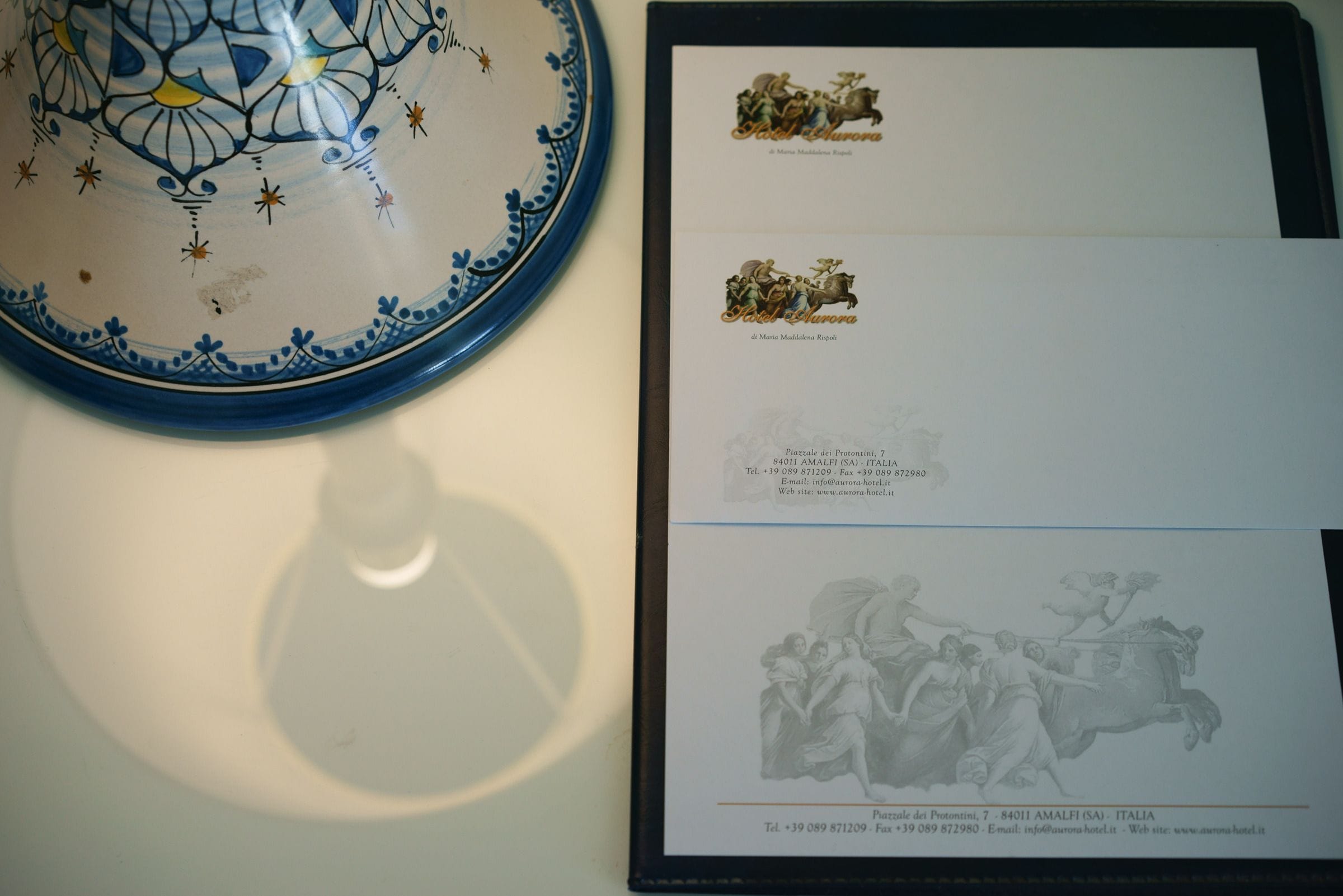 Un folleto de hotel enmarco con información de contacto y un plato decorativo.