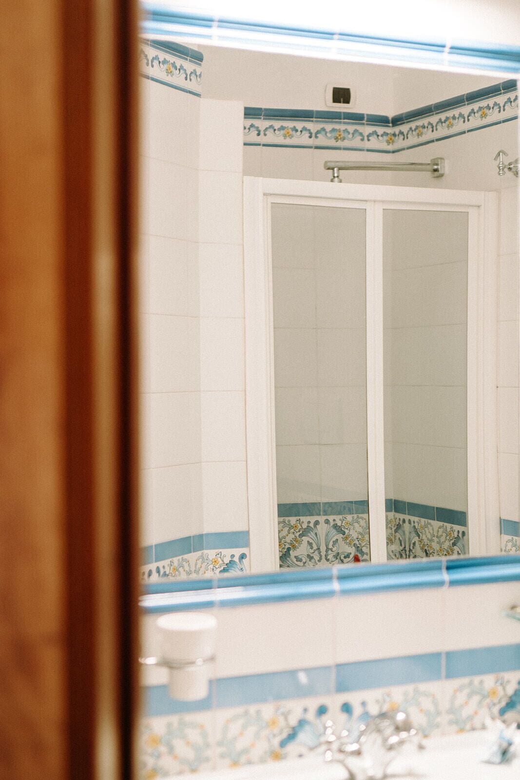 Casa de banho com porta branca, azulejos com padrão azul e branco e um rolo de papel higiénico visível.