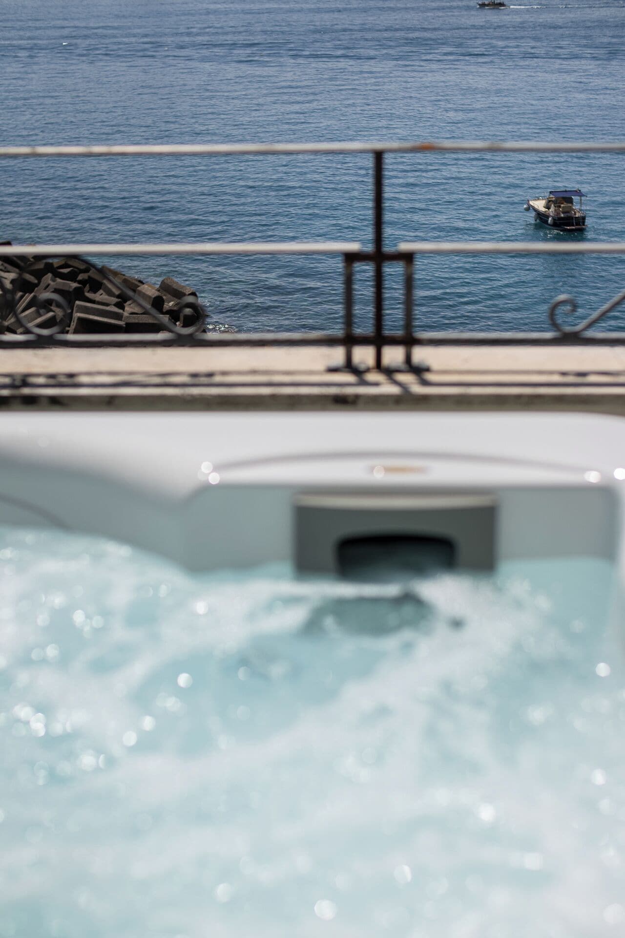 Una piscina con un jacuzzi, una baranda de metal y un barco al fondo.