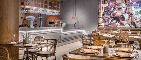 A restaurant with wicker chairs, a bar area, and a large mural on the wall.