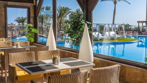Un espace repas aménagé au bord de la piscine, avec des meubles en osier et une vue sur la piscine.