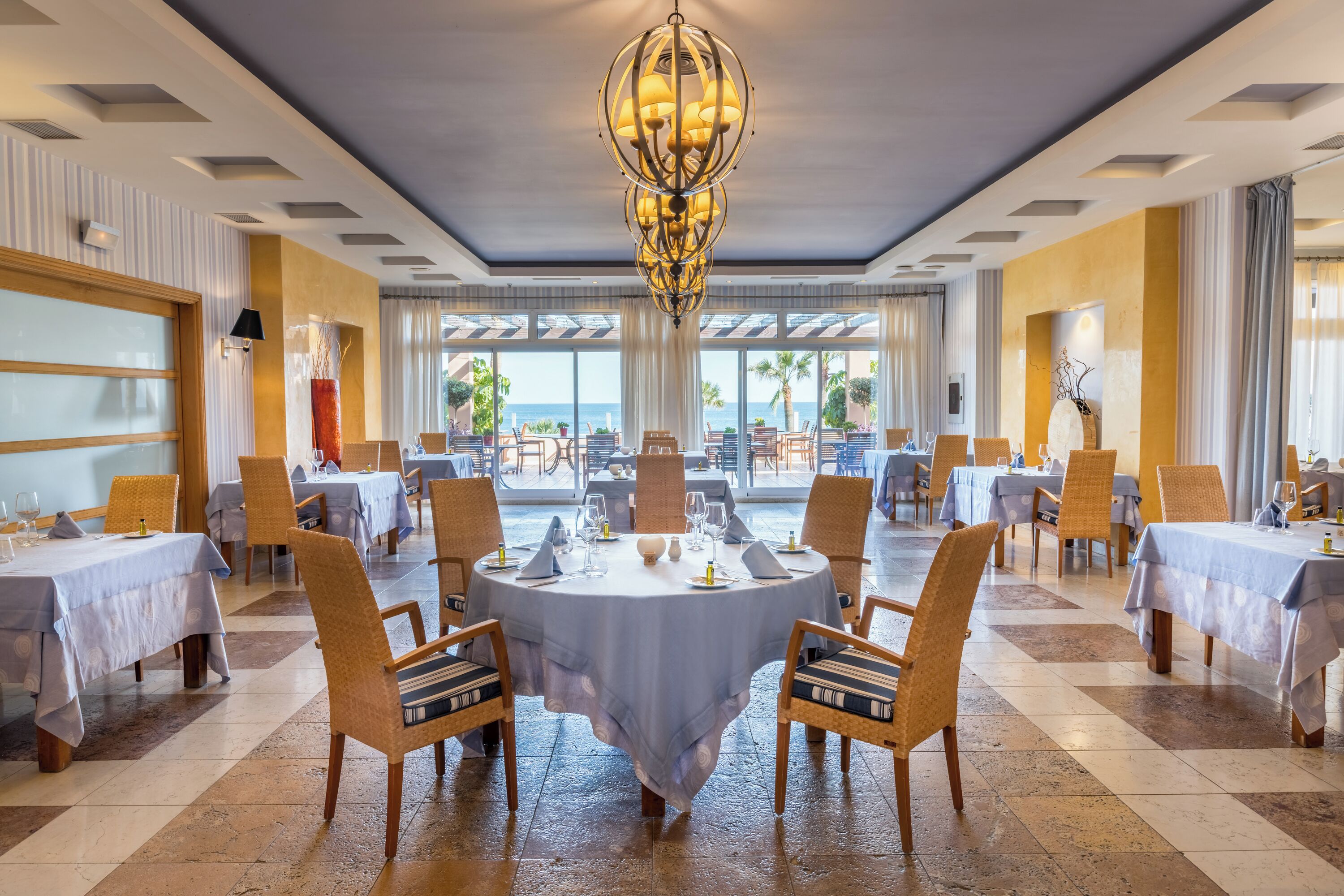 A dining area with round tables, chairs, and a chandelier.