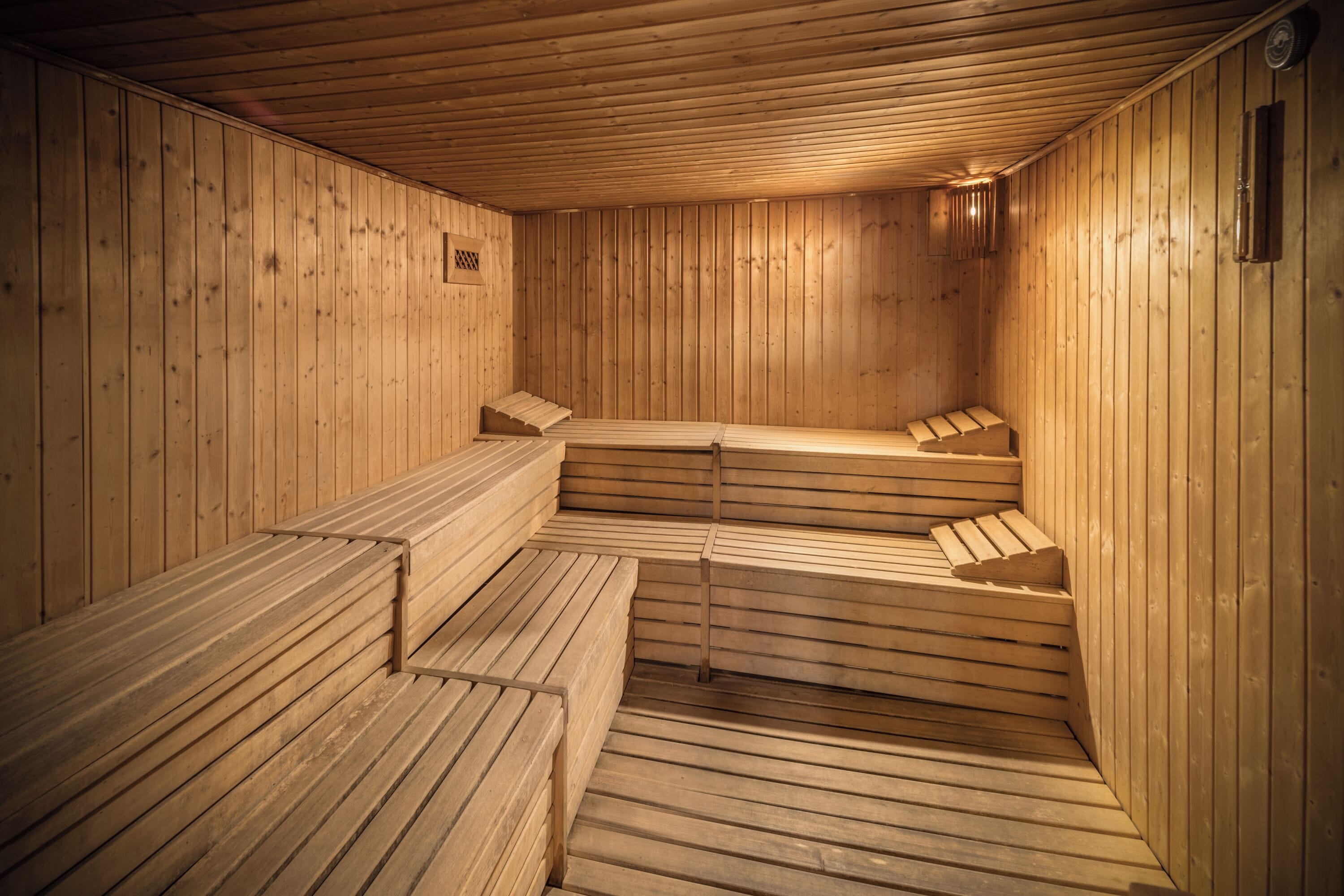A sauna with wooden benches and walls, a small window, and a ventilation system.