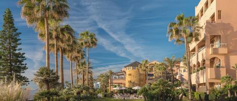 A resort with palm trees, a pool area, and a building with balconies.