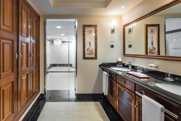 A modern bathroom with wooden cabinets, a large mirror, and a black countertop. - Gran Hotel Elba Estepona Thalasso & Spa (Estepona)