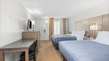 Une chambre d’hôtel avec deux lits, un bureau, une chaise, une télévision et une salle de bain.